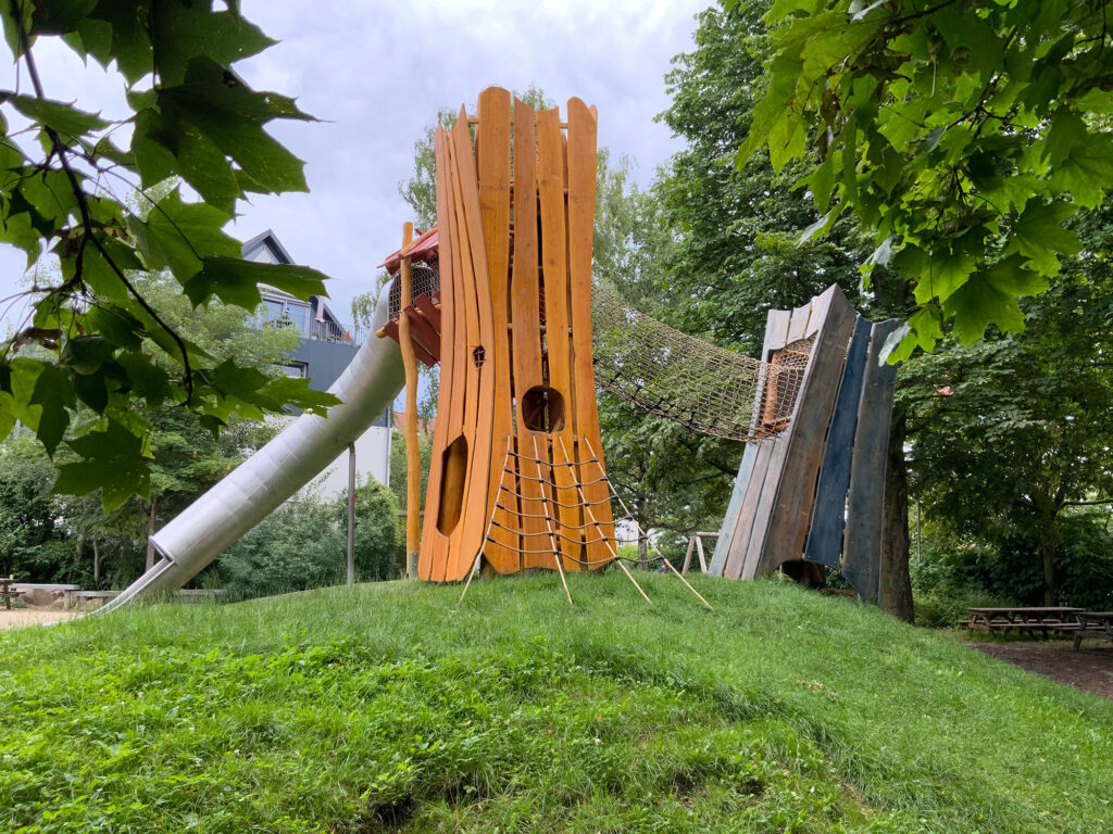 Großer Doppelturm mit Tunnelrutsche auf einem Hügel.